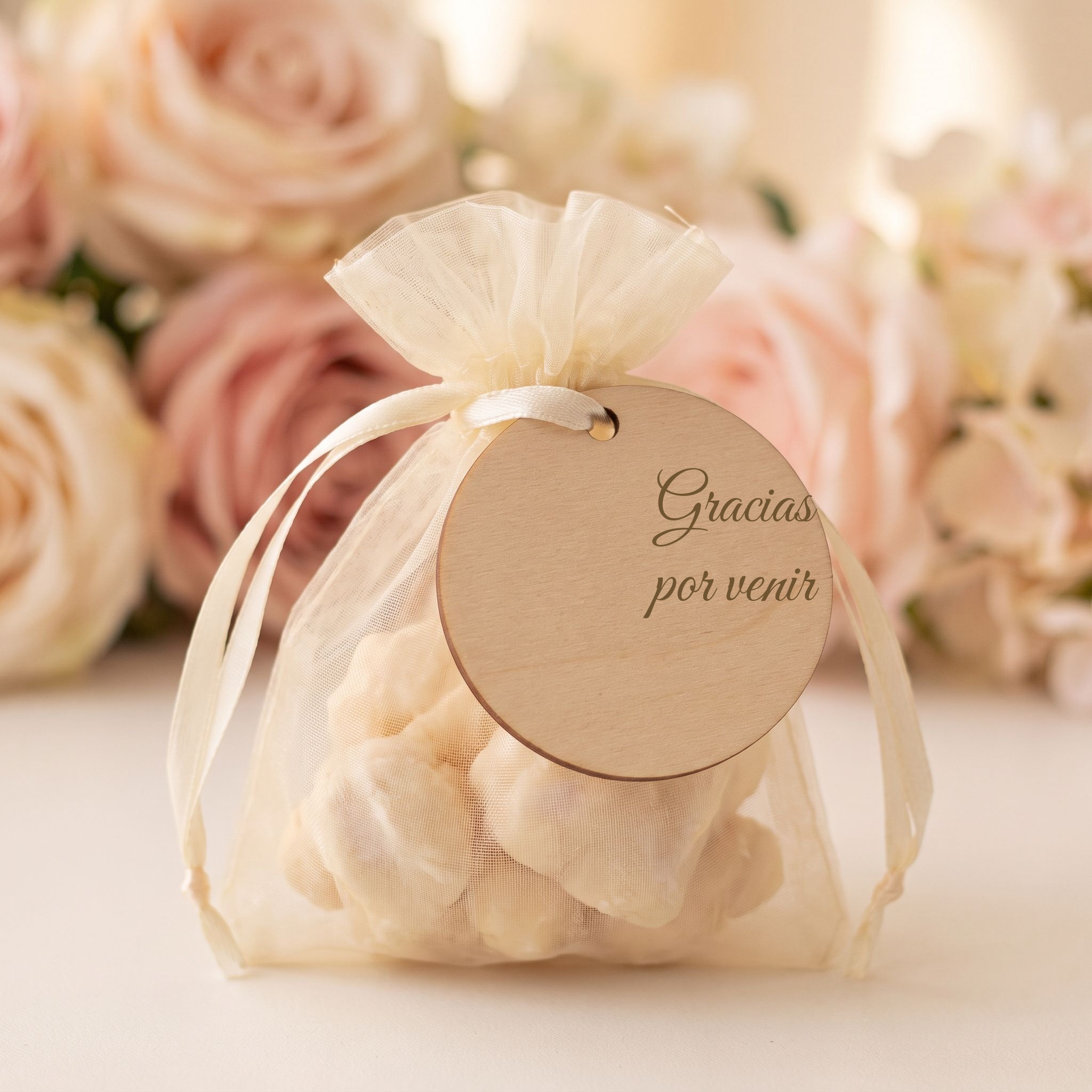 Recuerdito personalizado: bolsita de organza con lazo dorado y etiqueta para los invitados